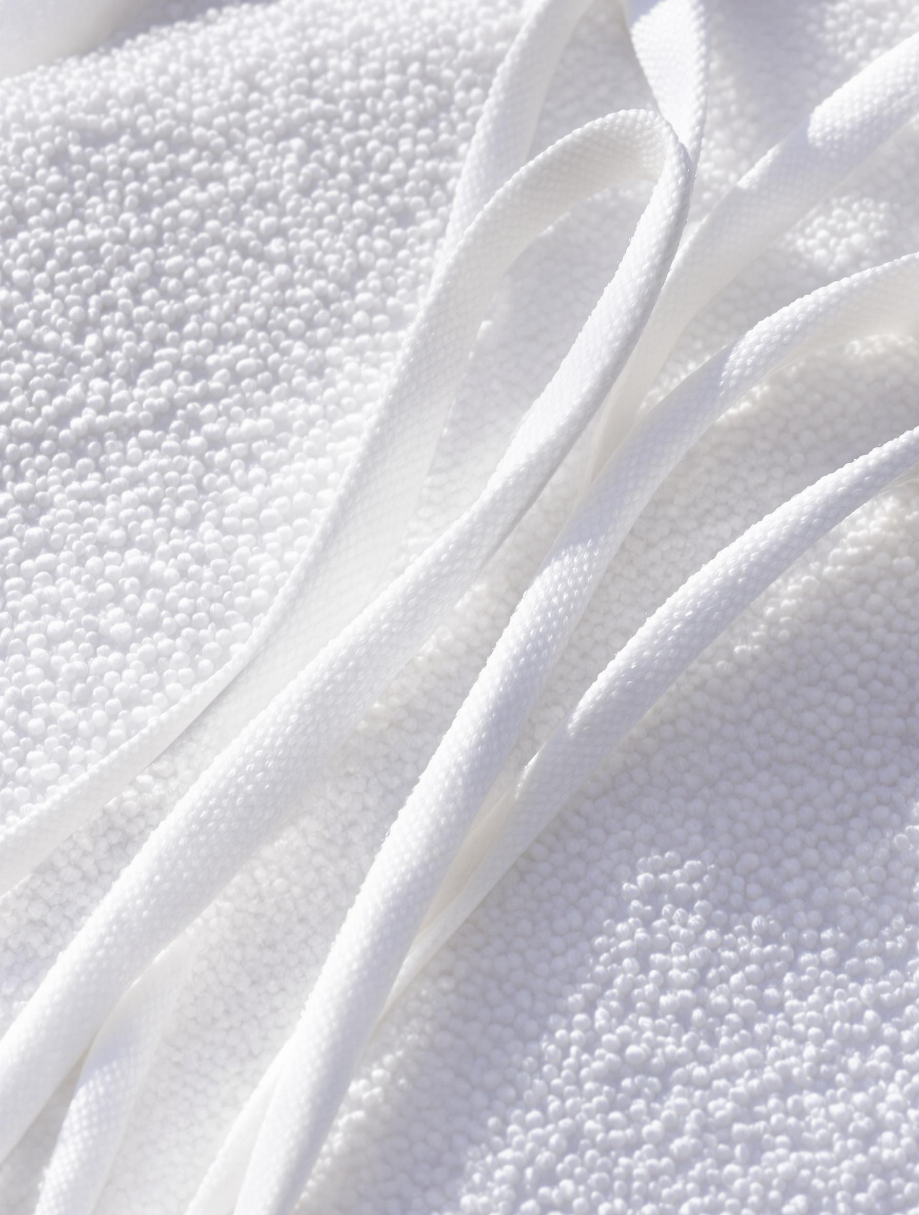 Lacets blancs fraîchement lavés séchant à plat sur une serviette microfibre