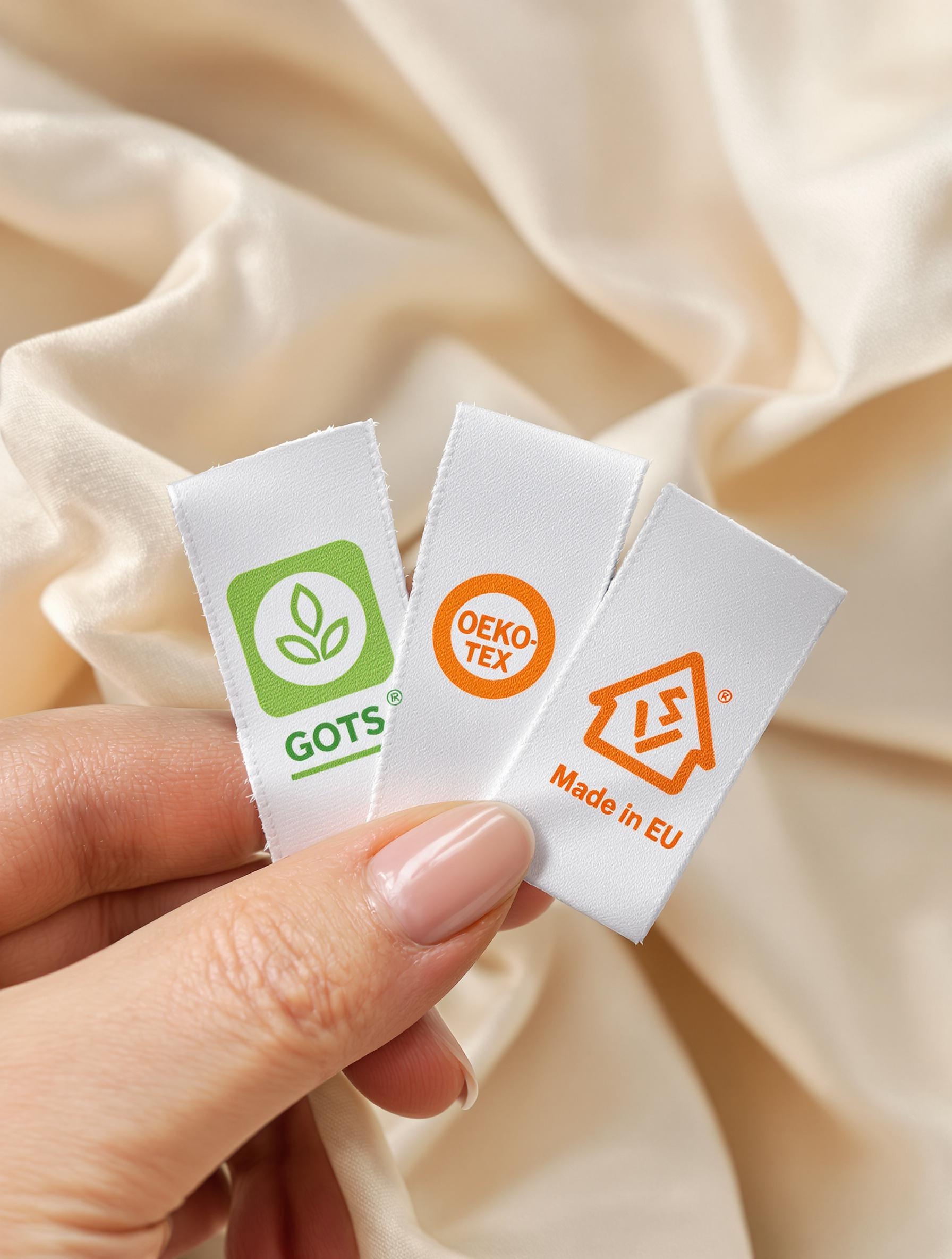 Main tenant étiquettes GOTS OEKO-TEX Made in EU