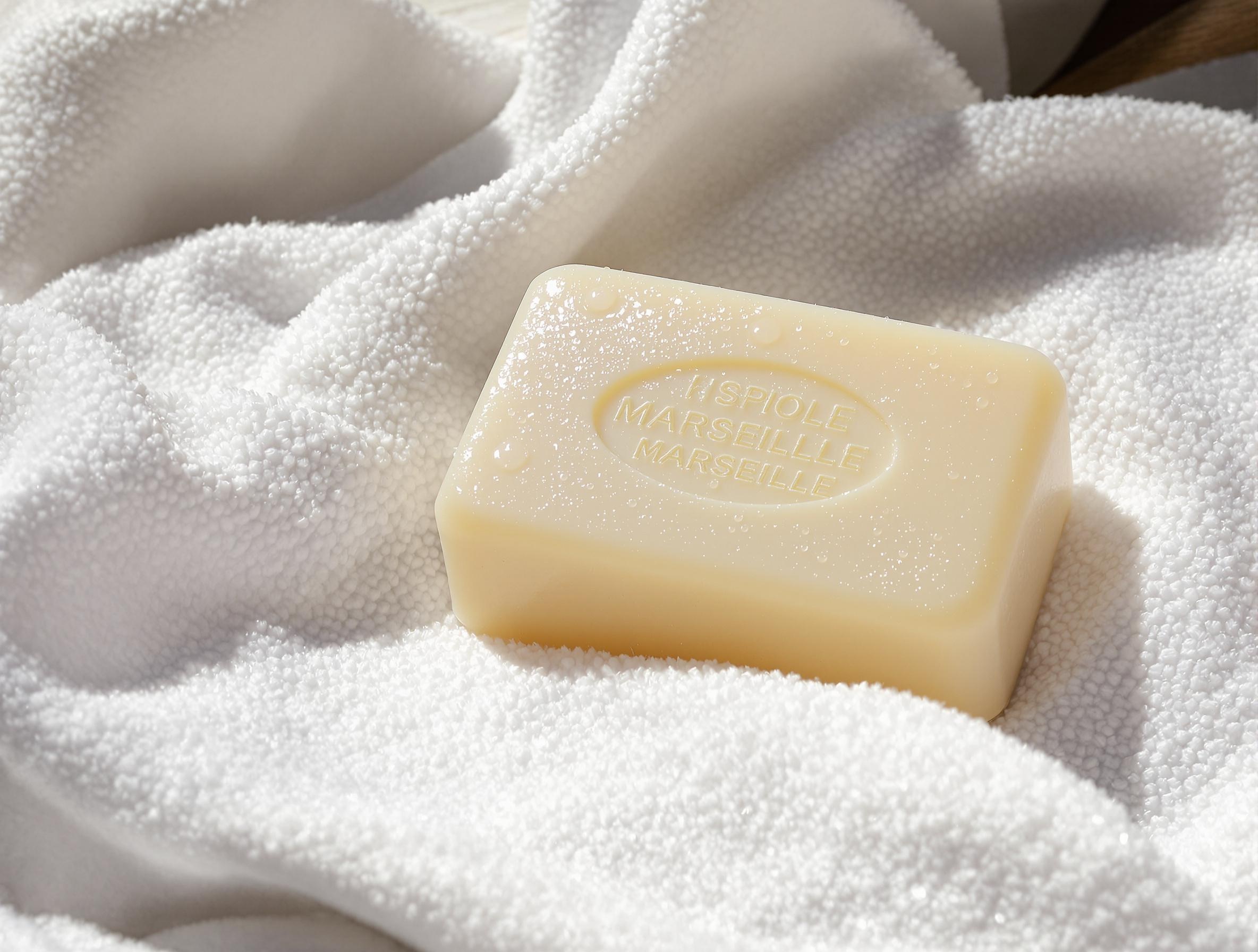 Barre de savon de Marseille humide posée sur un tissu micro-fibres blanc